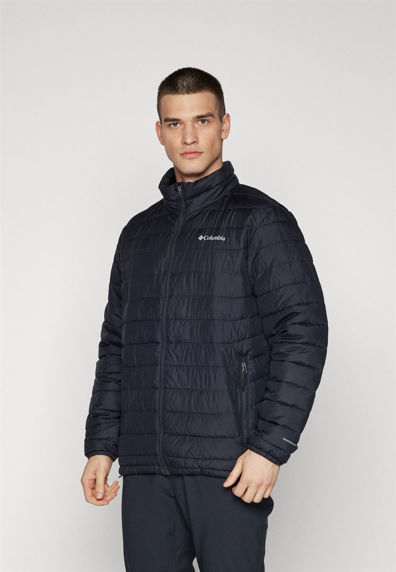 Giacca puffer di un blu navy scuro con colletto alto, apertura frontale con zip, design a trapunta a fantasia e logo sul lato sinistro del petto. Presenta tasche laterali.