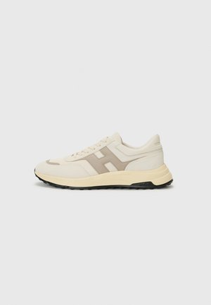 Beige athletic shoes featuring a smooth fabric upper, contrasting taupe accents, and a rubber sole with textured tread.