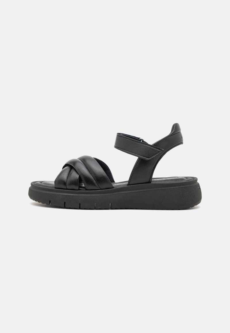 Black leather sandals with crisscross straps, adjustable ankle strap, and a thick, textured black sole. Minimalist design with no embellishments.