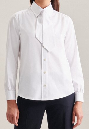 Blusa bianca a maniche lunghe con collo annodato, chiusura frontale con bottoni e tessuto morbido. Orlo dritto con maniche a cuffia e senza motivi visibili.