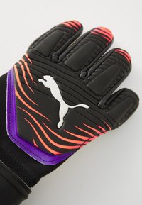 Svart keeperhanske med teksturert grep, med oransje og lilla bølgemønstre og en hvit Puma-logo på håndleddet.