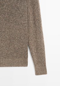 Brauner Strickpullover mit gerippten Bündchen und Saum, der aus einem strukturierten Stoff gefertigt ist. Das Design umfasst einen Rundhalsausschnitt und lange Ärmel.
