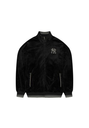 Black velvet zip-up jacket with a stand collar, striped cuffs, and a embroidered logo on the chest. Features side pockets with zippers.