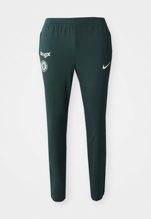 Pantalons de sport verts en tissu ribbé, arborant un logo Nike, un blason de Chelsea FC et une marque BingX sur le côté gauche.
