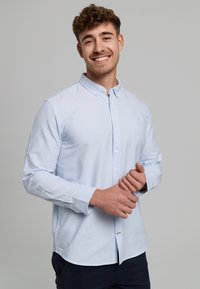 Hellblau-weiße gestreifte Button-Down-Hemd aus Baumwolle mit Kragen, langen Ärmeln und einer lässigen Passform. Hat eine weiche Textur.