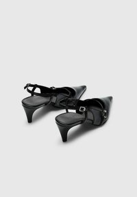 Melnas ādas slingback papēži ar smailiem pirkstiem, zemu papēdi, regulējamiem sprādžu siksniņām un gludu teksturētu apdari.