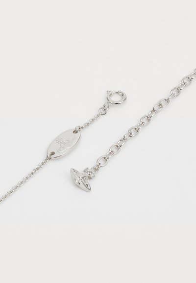 Silver chain bracelet with oval tag and a clasp, features a small UFO charm, smooth surface, and interlocking links.