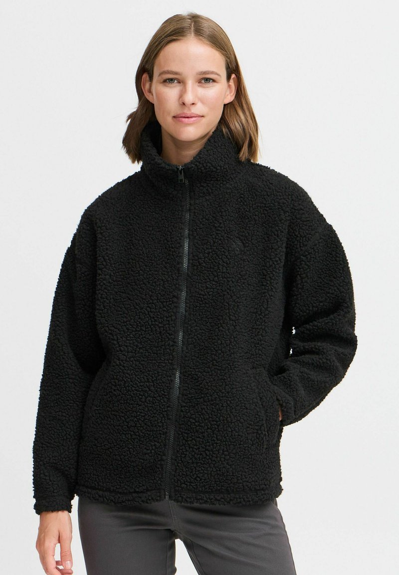 Veste en polaire noire avec un col montant, fermeture zippée intégrale et surface texturée. Présente des poches latérales et une coupe décontractée.