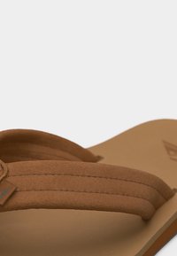 Κοντινή λήψη καφέ σαγιονάρας με μαλακούς υφασμάτινους ιμάντες και ραμμένες λεπτομέρειες σε ταμπά σόλα.