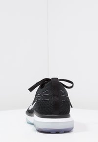 Scarpa da corsa nera con tomaia in maglia testurizzata, logo swoosh bianco e suola in gomma trasparente. Presenta lacci e una linguetta sul tallone.