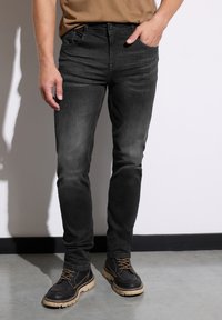 Mörkgrå denimjeans med smal passform, utrustade med klassisk femficksdesign och subtila blekningar, kombinerade med svarta läderstövlar.