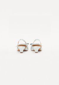 Talons en satin argenté avec un petit talon bloc arrondi, dos ouvert et bride de cheville réglable ; texture lisse avec une semelle en bois.