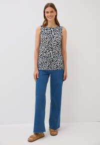 Top senza maniche con un motivo a stampa leopardata blu navy e bianco, abbinato a jeans larghi blu e sandali marroni. Tessuto morbido e leggero.