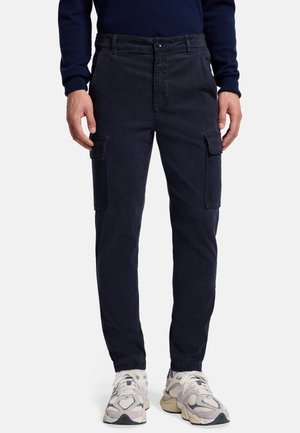 Navy cargobroek in katoen, met zijvakken, een knoopsluiting en een tapered fit, gecombineerd met beige sneakers.