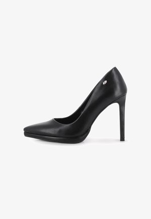 Zapato de tacón alto de cuero negro con punta afilada y tacón delgado tipo estilete, que presenta un pequeño logo metálico cerca del tacón.