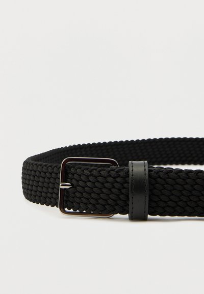 Črni tkan pas z izrazito pravokotno kovinsko sponko in usnjenim dodatkom. Teksturiran material z pletenim vzorcem.