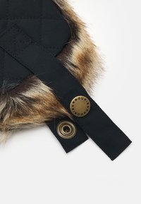 Wytłaczany czarny materiał z futrzanym wykończeniem, z czarnym paskiem i metalowym guzikiem z napisem "Barbour". Gładka tekstura i kontrastujące materiały.