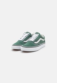 Grønn semsket sneakers har hvite snører, en hvit sidestripe, og svarte detaljer. Skoen har en klassisk lav topp-design og gummisåle.