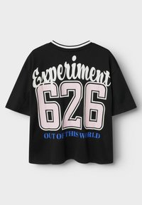 T-shirt noir à manches courtes avec "Expérience 626" en rose et blanc, et "HORS DE CE MONDE" en bleu en dessous du numéro.