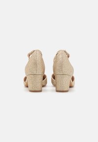Gold glitter high-heeled shoes with a rounded toe and ankle strap. Chunky heel and smooth, textured surface. Designed for formal occasions.