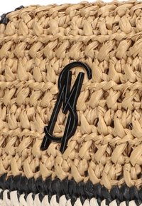 Geweven rieten handtas in een tan kleur, met een zwart logo-accent en een contrasterende donkere randafwerking. Textuur materiaal van natuurlijke oorsprong.