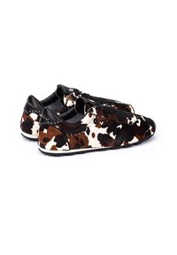 Zapatos sin cordones de piel de vaca con un patrón de manchas marrones y blancas, acentos negros y diseño de cordones. Presentan una superficie texturizada y una suela duradera.