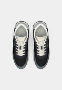 Pair of black and gray Calvin Klein sneakers with white laces and cushioned collars, viewed from above on a white background.