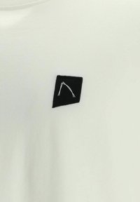 Weißes T-Shirt mit einem schwarzen Patch und einem einfachen weißen geometrischen Design. Weiche Textur mit klassischem Rundhalsausschnitt und kurzen Ärmeln.
