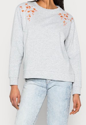 Sweatshirt gris clair à manches longues. Équipé de détails floraux orange brodés sur les épaules. Tissu doux, coupe décontractée.