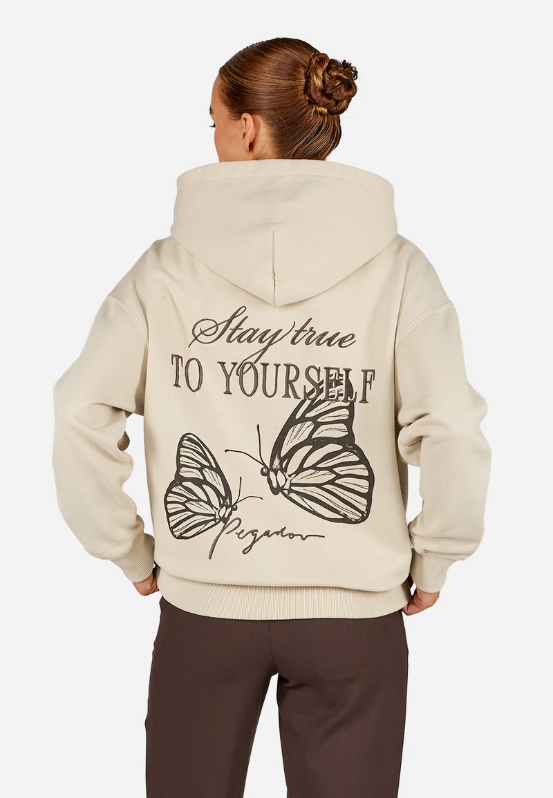 Μπεζ φούτερ με μεγάλη, γραφική εκτύπωση δύο πεταλούδων και το κείμενο "Μείνε πιστός στον εαυτό σου" στην πλάτη. Μαλακό, υφασματώδες υλικό.