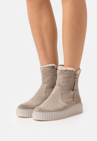 Botas de tobillo de ante gris con una suela de goma blanca texturizada, cremallera lateral y forro suave en el puño.