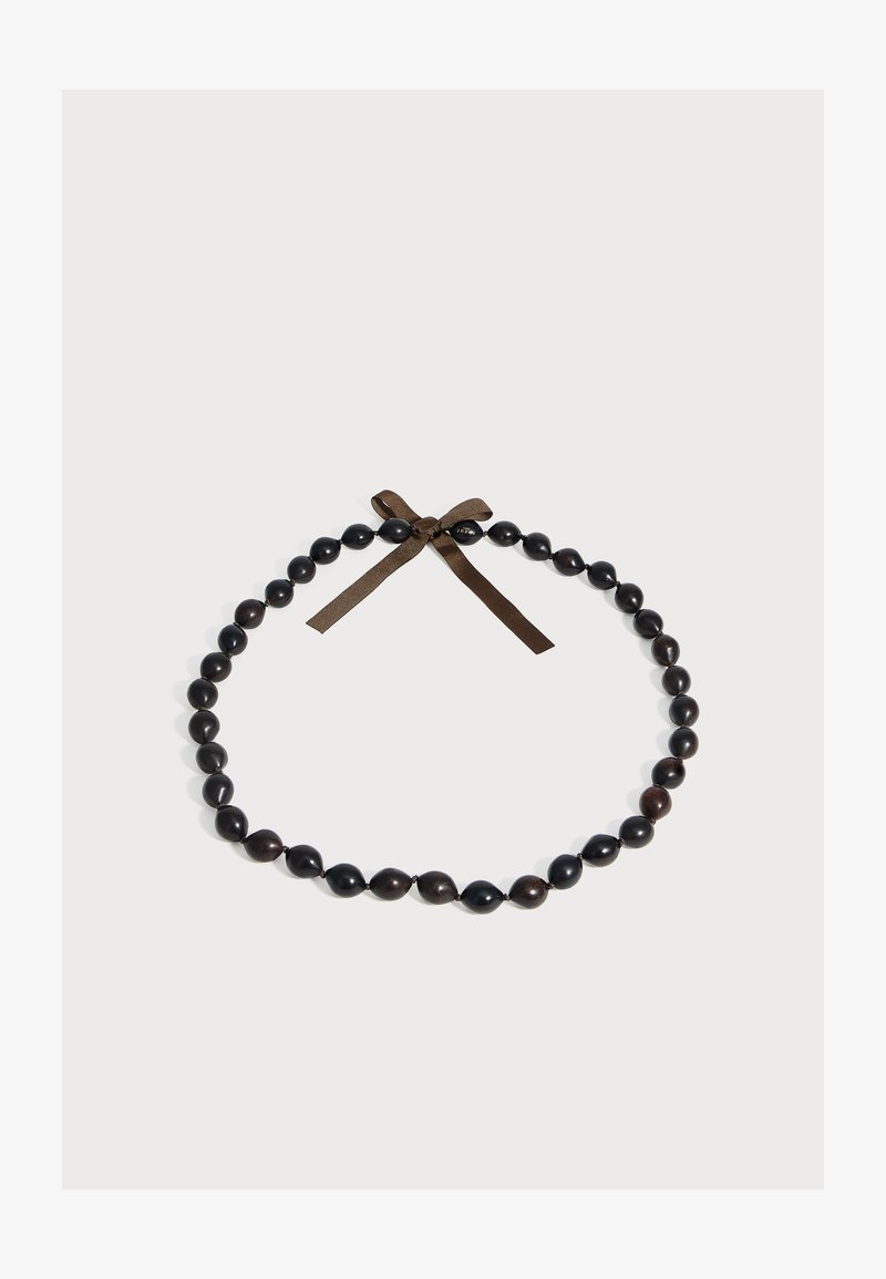 Collier de perles en bois foncé avec des perles ovales, attaché avec un nœud en ruban marron sur un fond gris clair.