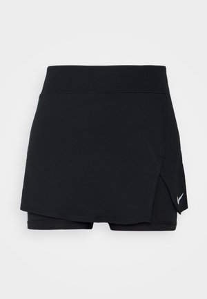 Skort deportivo negro con pantalones cortos integrados, que presenta una banda ancha en la cintura, un diseño envolvente y un pequeño logo blanco en la esquina inferior derecha.
