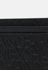 Portafoglio nero texturizzato con motivo logo in rilievo, realizzato in materiale sintetico con finitura liscia e dettagli di cucitura orizzontale.