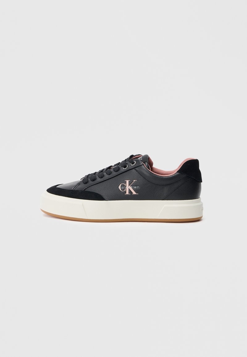 Baskets basses noires avec semelle blanche épaisse, lacets noirs et doublure intérieure rose, avec logo Calvin Klein sur le côté.