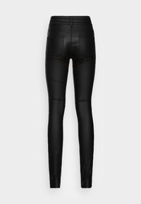 Leggings negros de cintura alta con una textura suave y elástica. Cuenta con dos bolsillos traseros y un diseño ajustado que se ciñe en los tobillos.