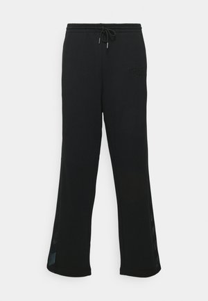 Pantalons de survêtement noirs en tissu doux, dotés d'une taille avec cordon de serrage, d'une coupe évasée et d'accents en mesh sur les côtés.