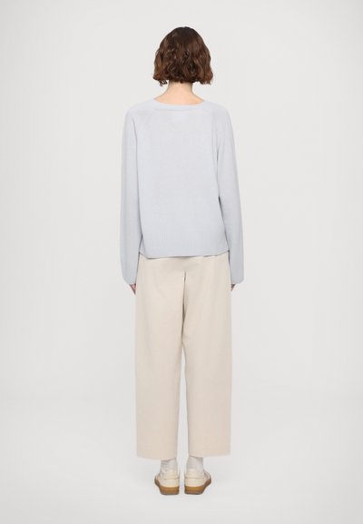 Heleheline kootud sviiter ringja kaelusega, ribakrae ja pikkade varrukatega, koos beežide laia säärega pükstega ja kreemjate kingadega.