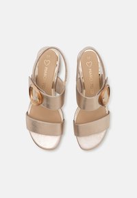 Gold metallic sandals with two wide straps and a circular accent. Open heel design and flat sole. Size marked as 37 inside.