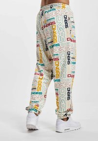 Colorful jogger pants with an elastic waistband, featuring a mix of logos in red, green, and yellow on a light background. 秒速