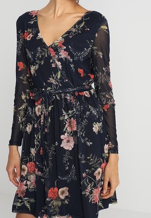 Marineblauwe bloemenprint wikkeljurk met lange doorschijnende mouwen, V-halslijn en ceintuur om in de taille te strikken.