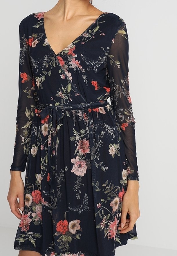 Robe portefeuille bleu marine à fleurs avec manches longues transparentes, col en V et ceinture à nouer à la taille.