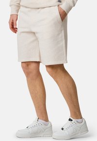 Ljusbeiga bomullsshorts med sidfickor och elastisk midja. Bärs med vita sneakers med svarta detaljer.