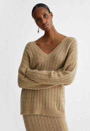 Maglione beige lavorato a maglia con scollatura a V, design a costine testurizzato e maniche lunghe. Presenta un piccolo emblema del marchio all'orlo.