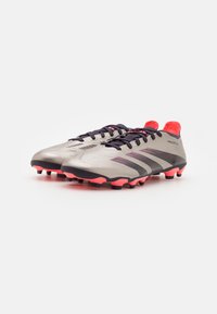Scarpini da calcio argentati con tomaia texturizzata, accenti neri e dettagli rosa vivaci. Presentano un profilo basso e un design affusolato per migliorare le prestazioni.