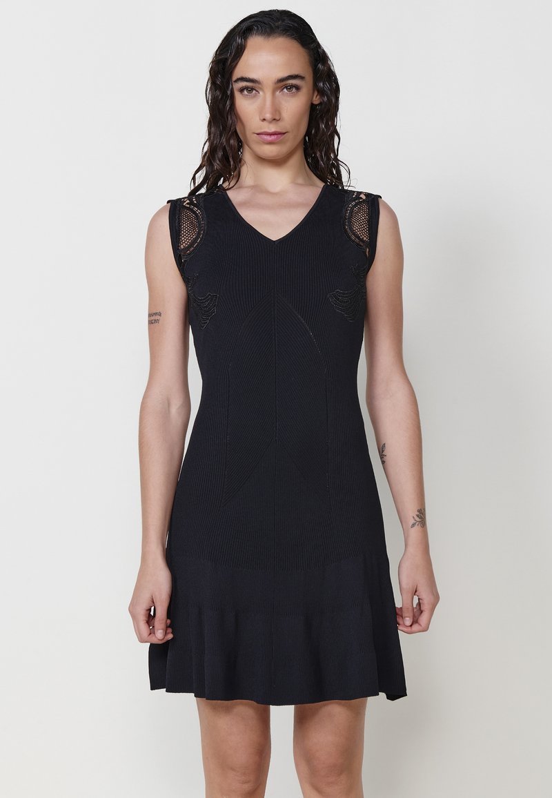 Schwarzes ärmelloses Kleid mit tailliertem Oberteil, V-Ausschnitt, gerippter Textur und Spitzenakzenten an den Schultern; ausgestellter Rock mit Rüschensaum.
