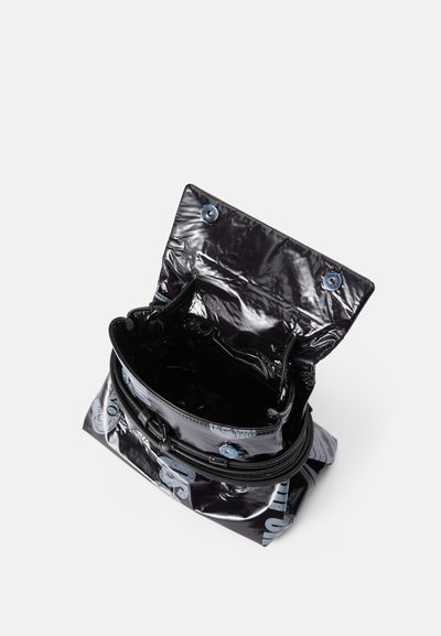 Musta kiiltävä laukku, joka on valmistettu kiiltävästä materiaalista, pyöreä muoto, vetoketjukiinnitys sekä siniset nappikoristeet läpällä ja hihnassa.