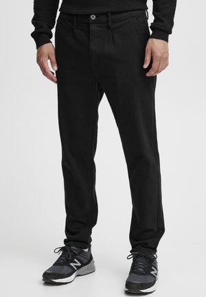 Black denim pants with a straight leg cut, featuring front pockets and a button closure. Worn with dark athletic shoes.