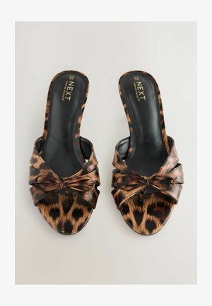 Mule z leopardjim vzorcem ter odprtim prstom, z vozelčnim detajlom na sprednji strani. Gladek črn podlog in mehak strukturiran material.