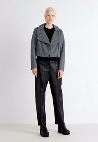 Gray cropped jacket with a textured finish, featuring a wide lapel and front zipper, paired with black leather high-waisted trousers and platform boots.